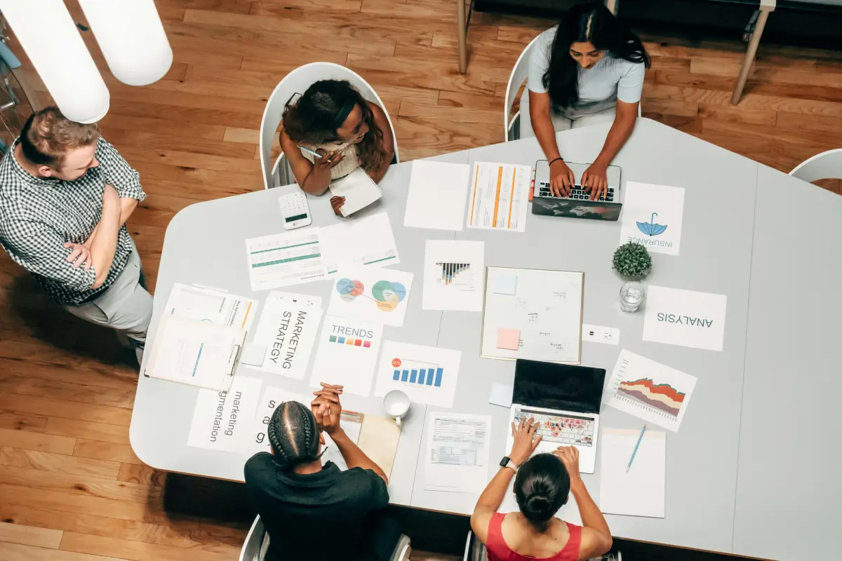 A birds-eye view of a team meeting around a white table.