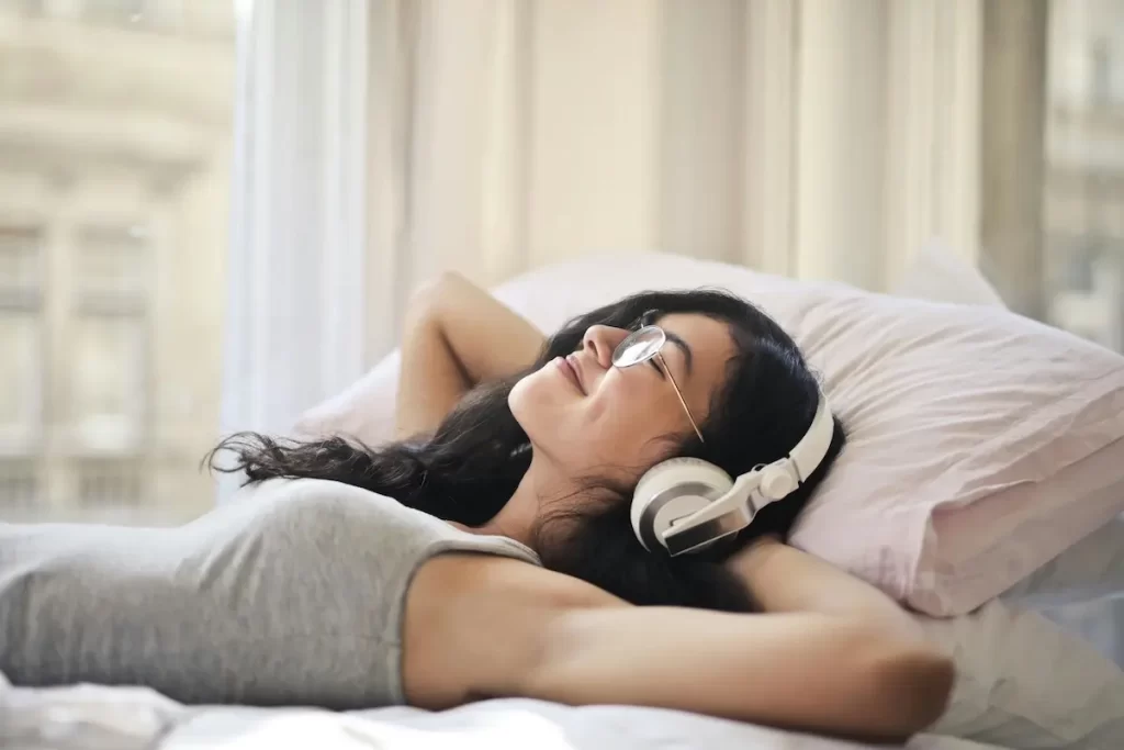A woman relaxing on her bed listening to music