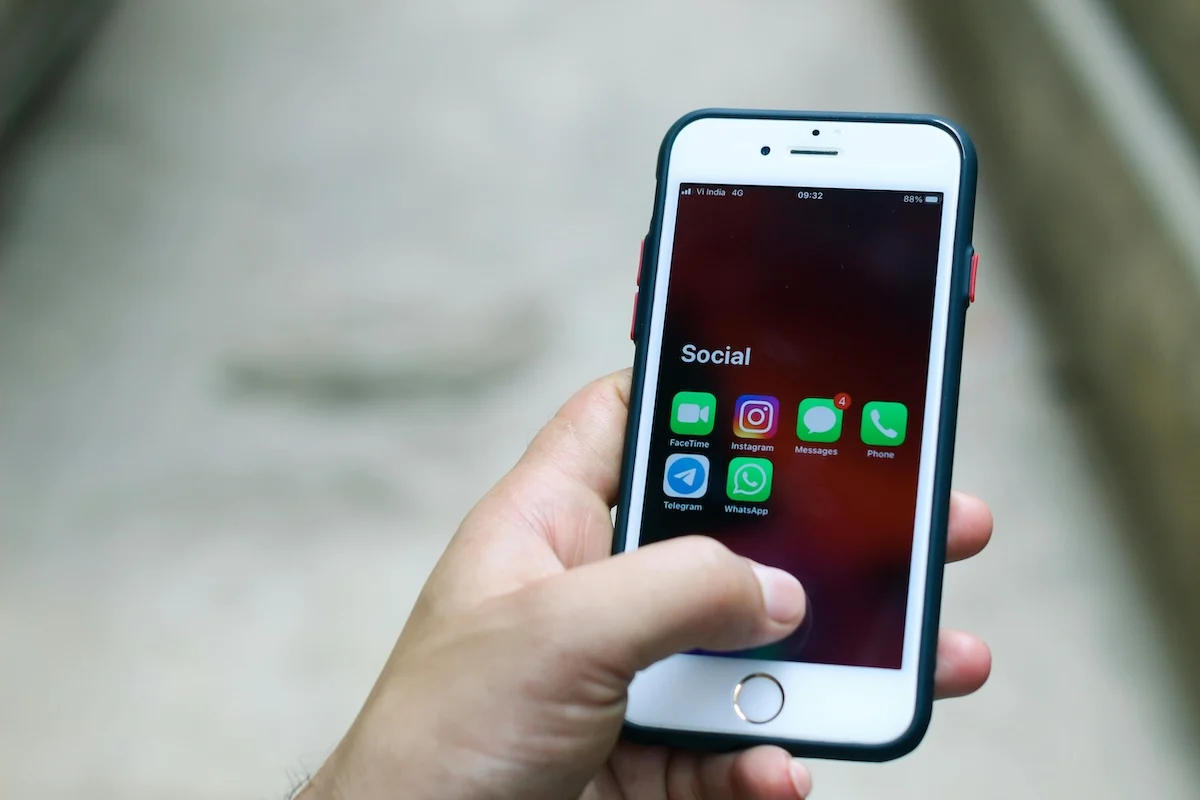 Hand holding a smartphone with social media apps, including Telegram