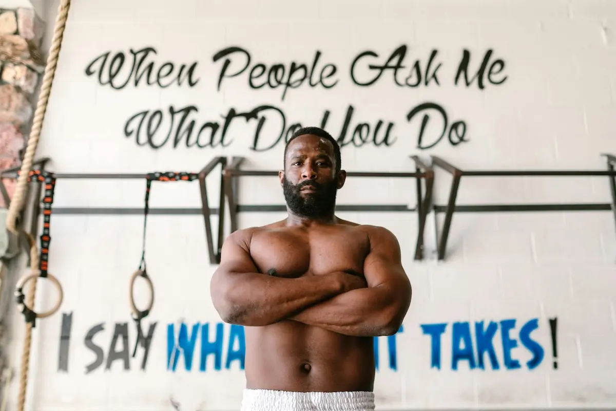 A strong black man with his hands folded in a gym