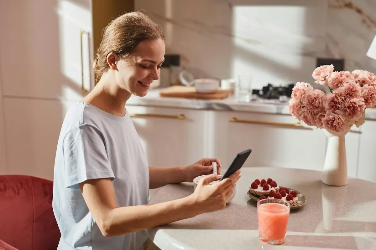 Woman sitting at a kitchen table enjoying being on her smartphone