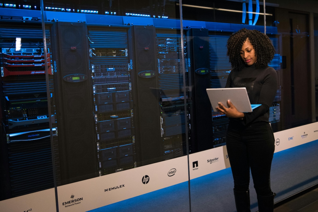 Woman standing by a super computer on her laptop