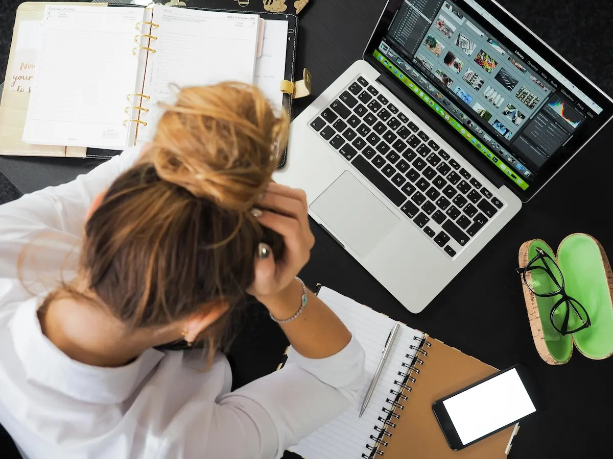 A dissatisfied woman with her head in her hands using a laptop