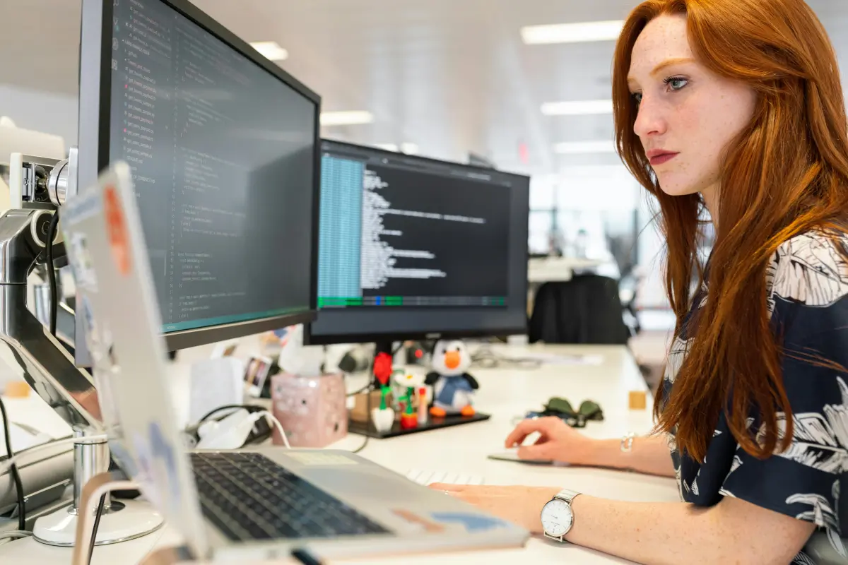 A woman working at a desk looking intently at the computer screen