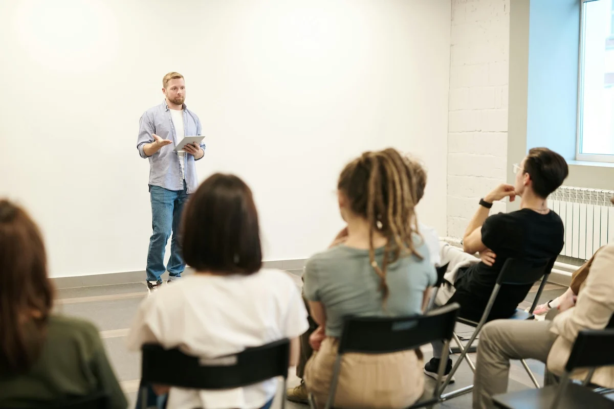White man speaking to an audience indoors