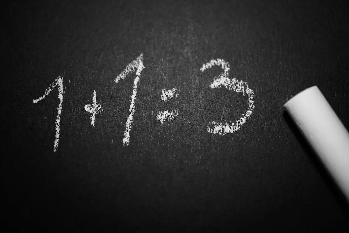 1 + 1 = 3 written in chalk on a blackboard
