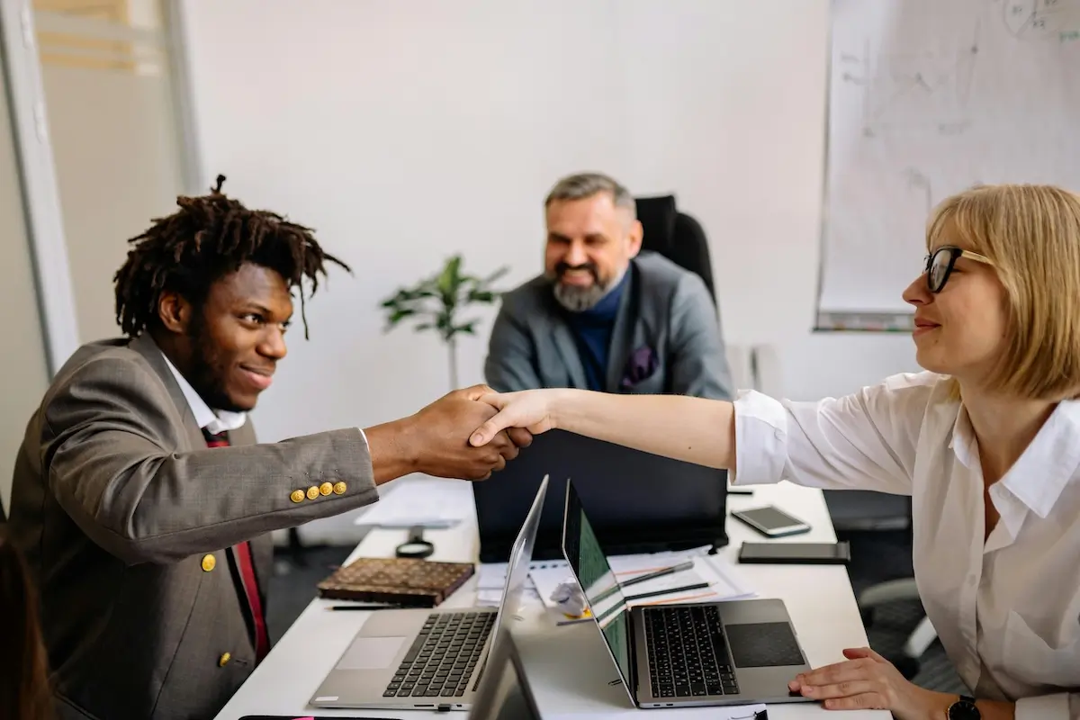 A man and woman shaking hands across a desk on sustainable energy by Yan Krukau on Pexels. com
