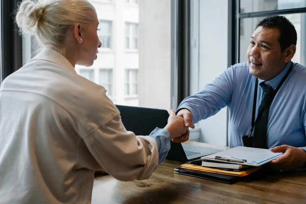 Woman and man shaking hands over a desk over a Ethereum contract by Sora Shimazaki on Pexels. com