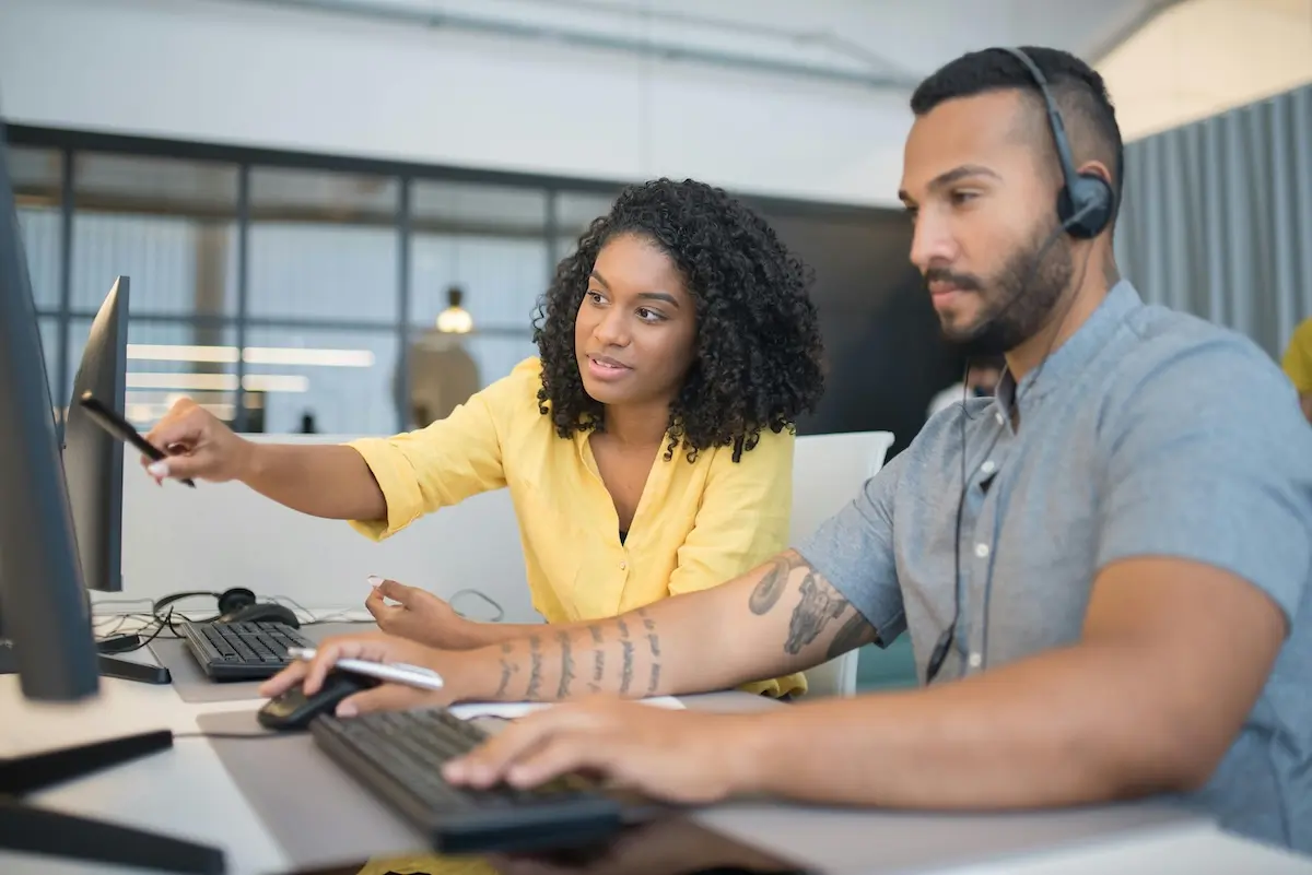 Woman helping a guy learn AI/ML while he's on the commputer