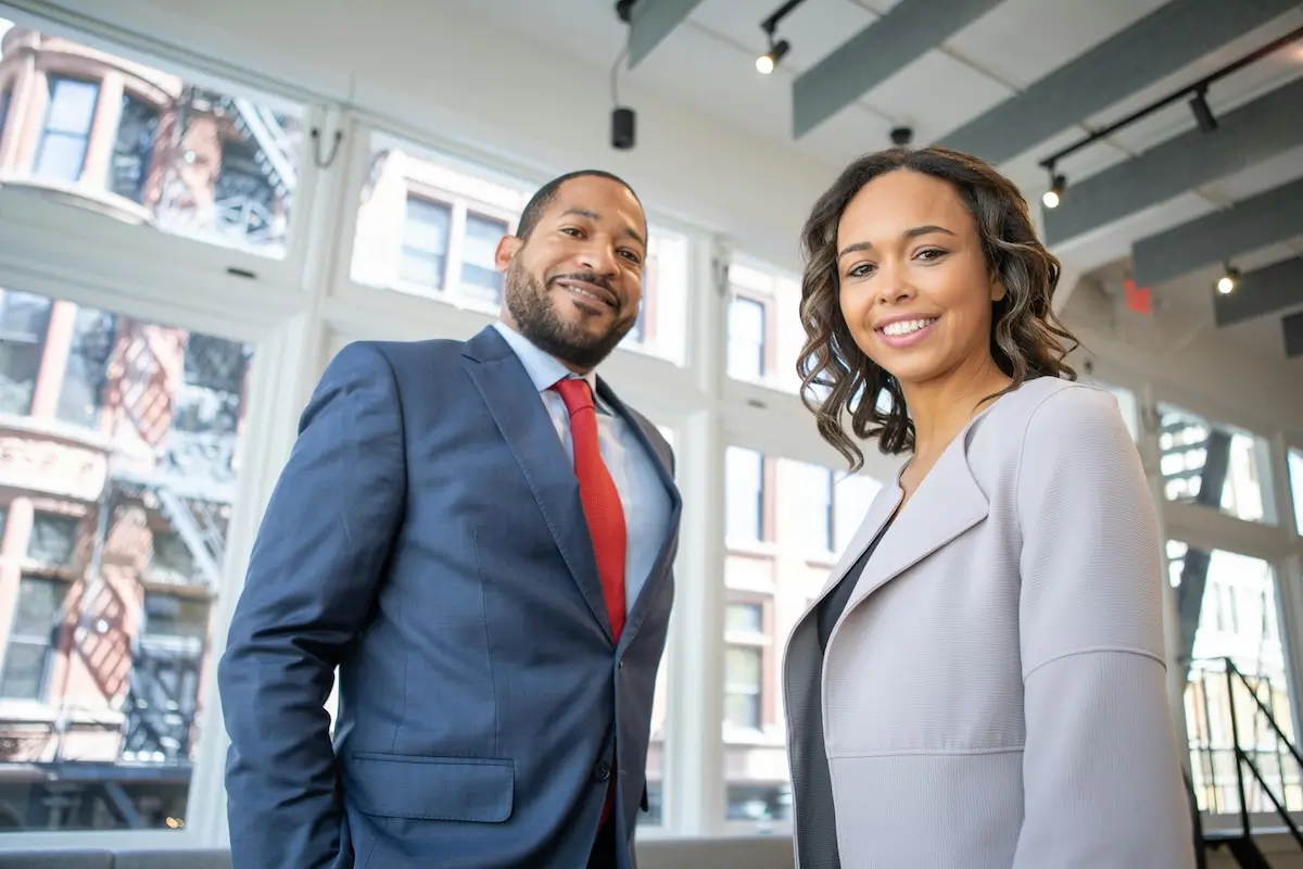 A business man and woman nsmiling at the camera by Rebrand Cities on pexels.com