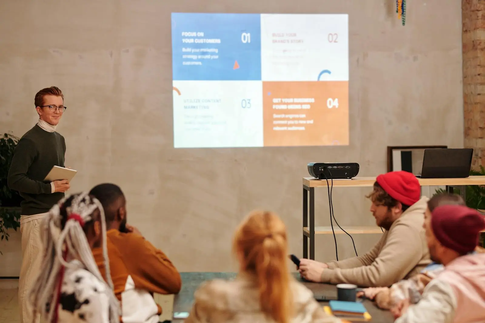 A Man in Black Sweater Standing Near the Projector Screen giving a presentation about AI Agents by Diva Plavalaguna on pexel.com