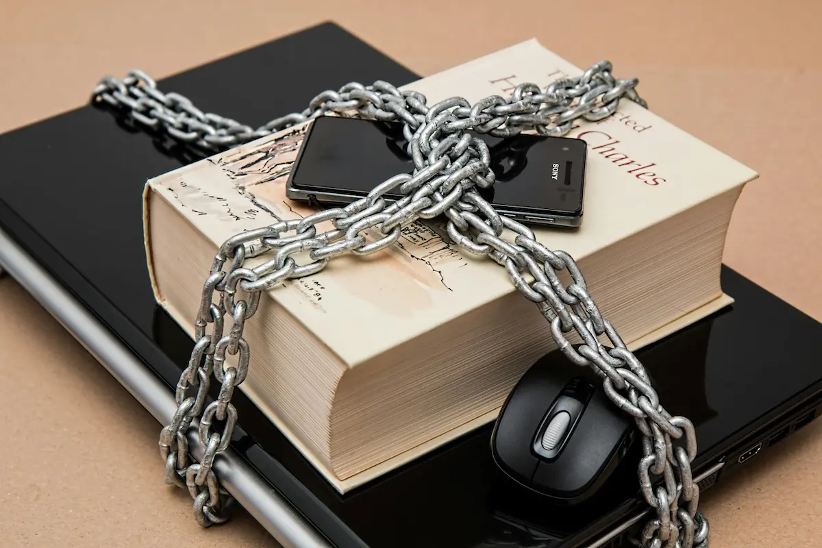 A phone, large book, and laptop locked togetehr with a cross chain by Pixabay on pexels.com