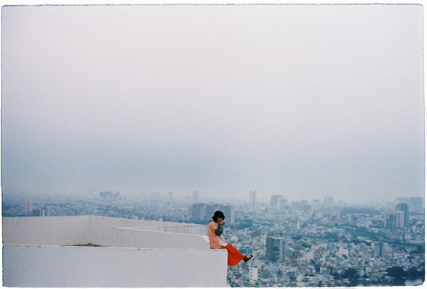 A woman sitting on the edge of a tall building signifying the risks of online payments by Ánh Đặng on Pexels