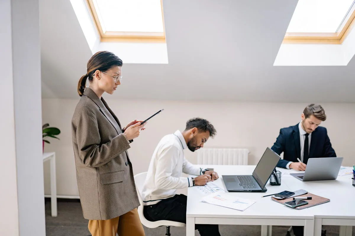 Woman in Brown Blazer Standing Beside Men Sitting at white Table reading Web3 Content by Yan Krukau