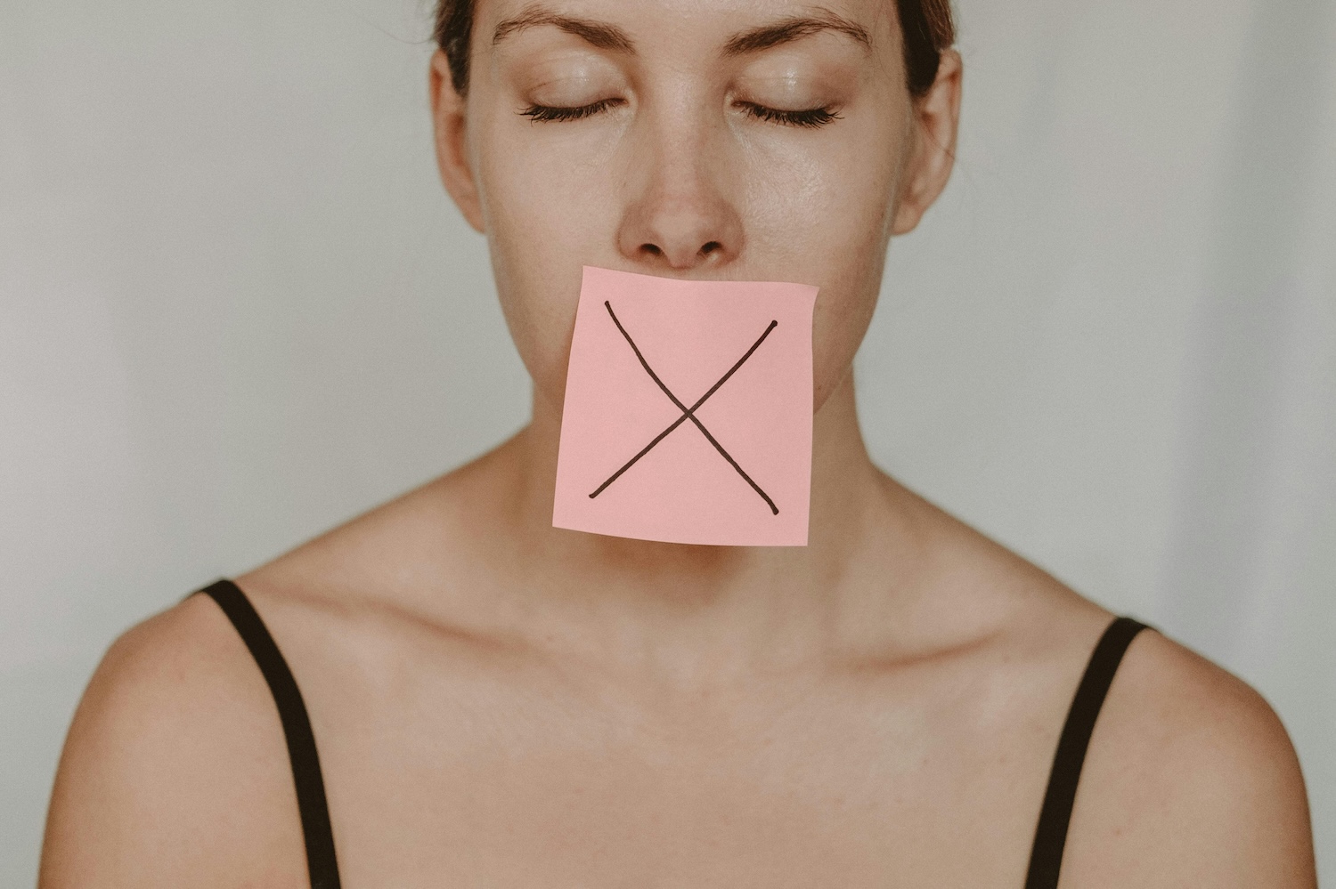 A woman with her eyes closed and a postage note over her mouth by Anete Lusina on pexels