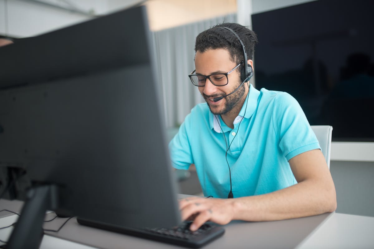 Man in Blue Polo Shirt with Headset on a Web3 site on his Computer by Kampus Production