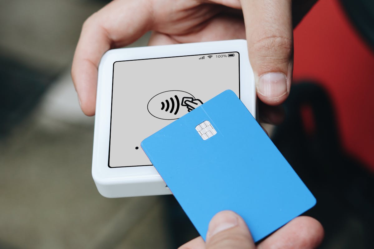 A person holding a blue card making payment using stablecoins by SumUp Payments