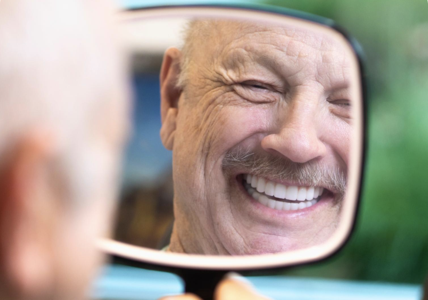 Smiling man admiring new full arch implants