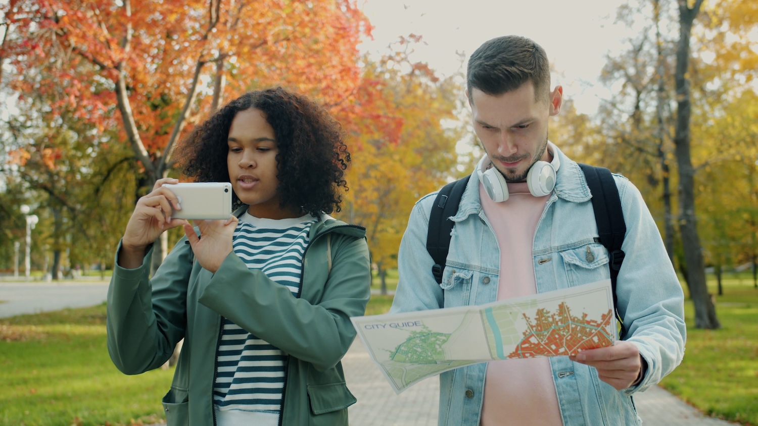 Two young people searching for somewhere using their celular and a map by Vitaly Gariev on pexels