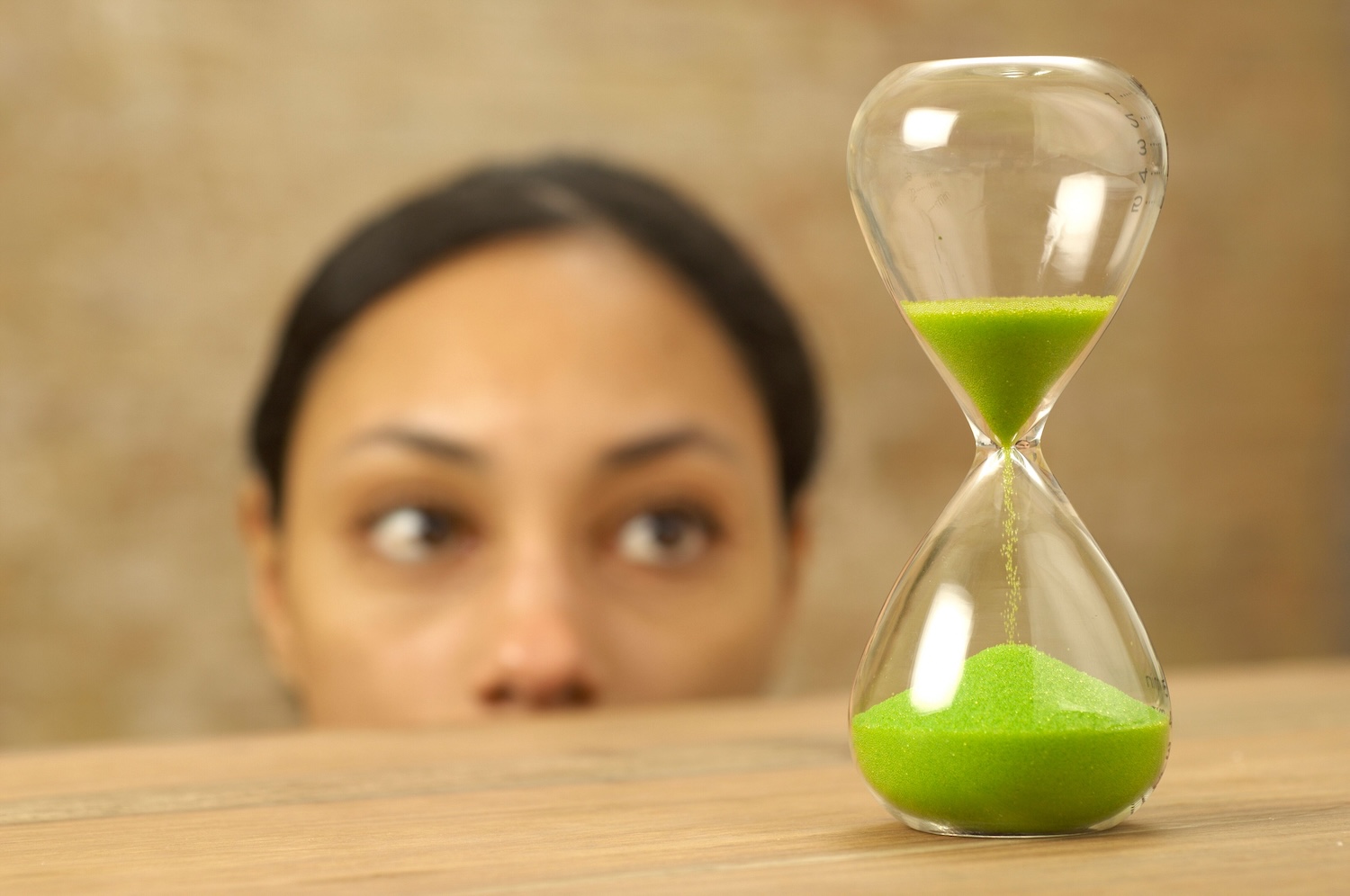 Woman staring at an hour glass with green sand over halfway through by BOOM 💥 Photography on Pexels