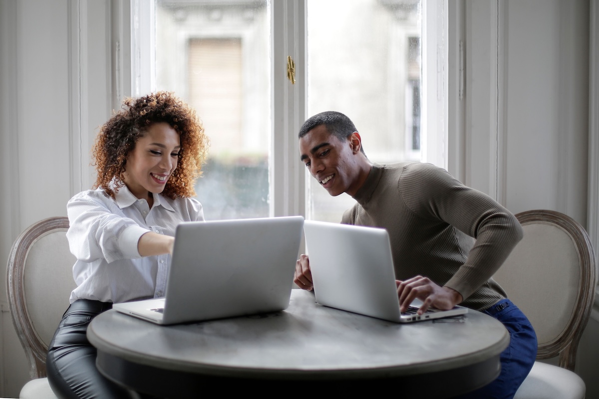 Woman of colour pointing at her laptop showing male friend the best email marketing tools by Andrea Piacquadio on Pexels